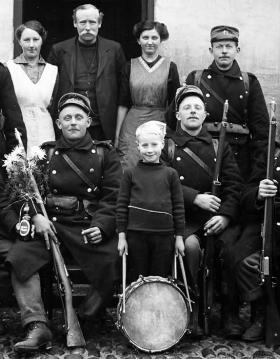 Eine Gruppe von Soldaten mit Gewehren und ein Junge mit einer Trommel